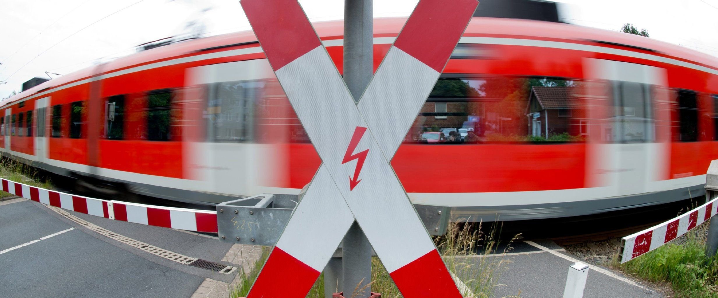 Ein Zug passiert an einem Bahnübergang ein Andreaskreuz.