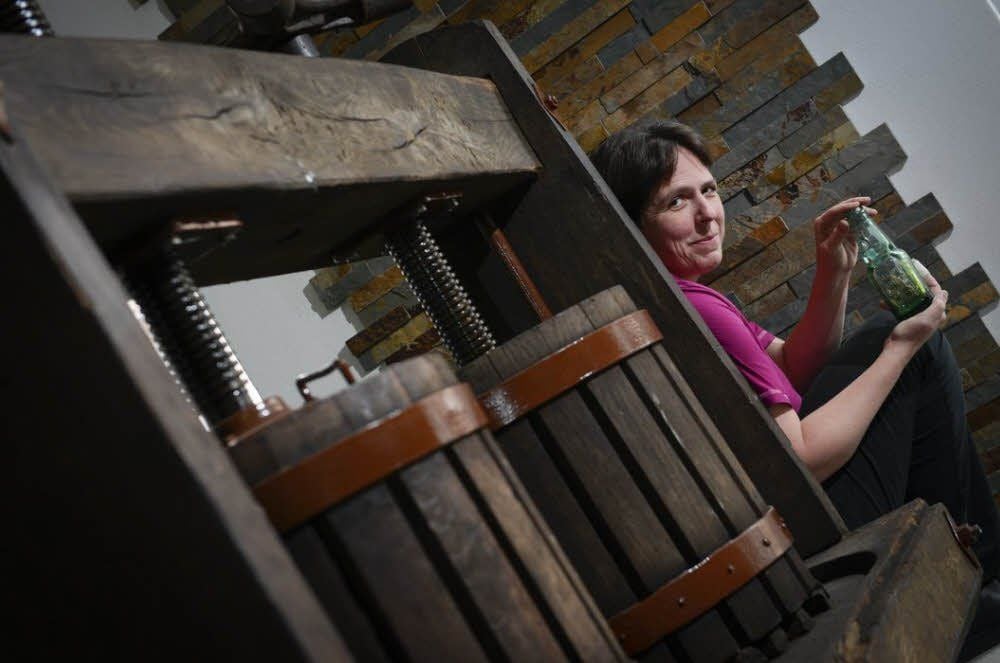 Nicola Hedemann mit einer originalen Gastrich-Brause-Flasche vor einer historischen Saftpresse fürs Museum.