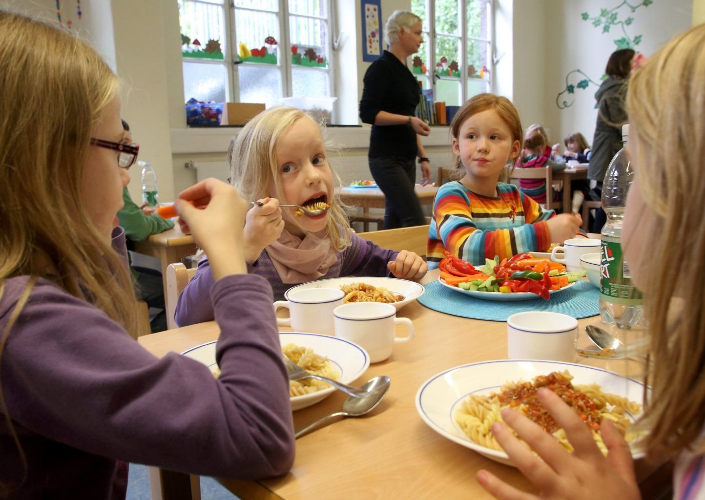 Kinder nehmen im Speiseraum einer Schule ihr Mittagessen zu sich.