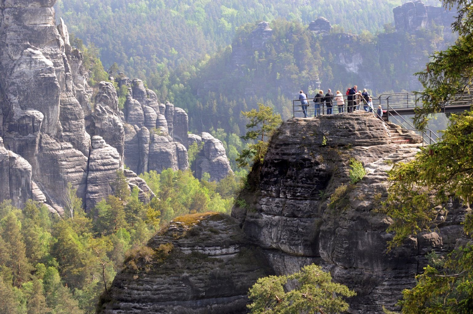 Touristen stehen auf einem Aussichtspunkt an der Bastei im Nationalpark Sächsische Schweiz.