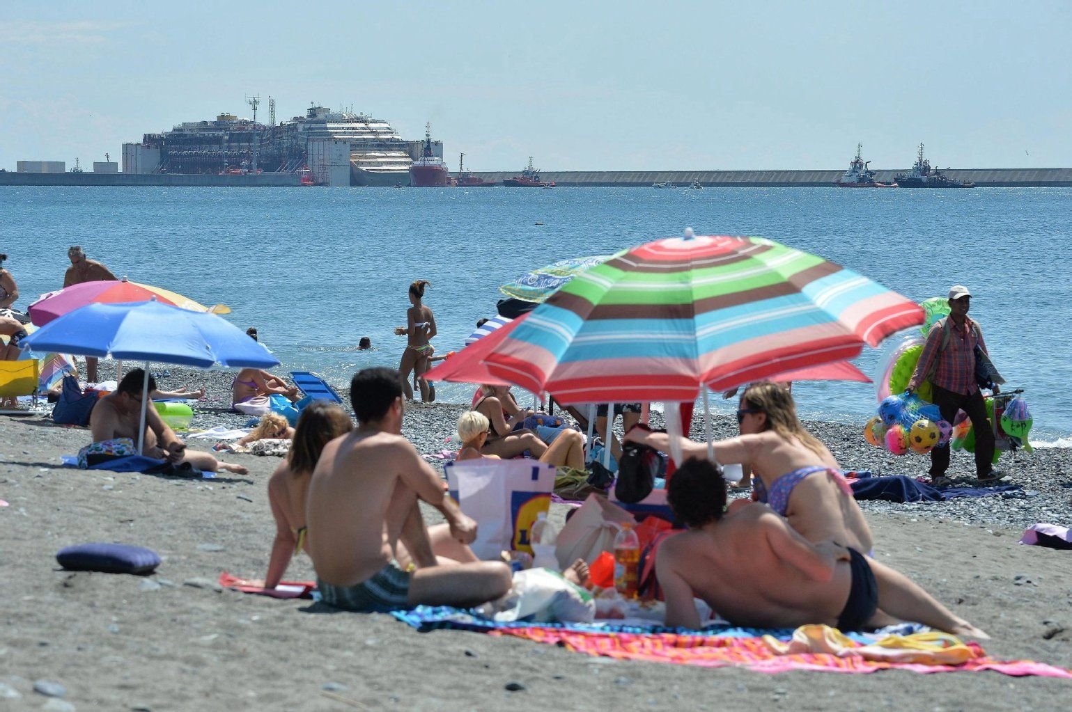 Strandtag mit Blick aufs Wrack: Die Costa Concordia wird in den Hafen von Genua gezogen.