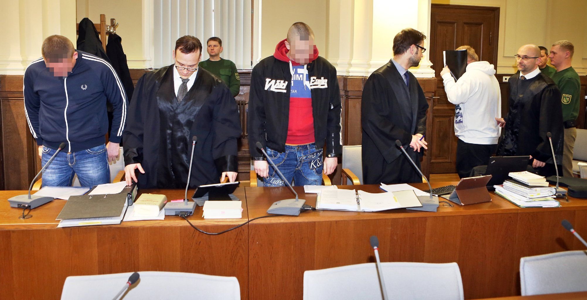 Die wegen Drogenschmuggels angeklagten Lars S. (l), Nico R. (M) und Peter M. (5.v.l.) stehen mit ihren Anwälten am Freitag zum Prozessauftakt im Landgericht Leipzig.