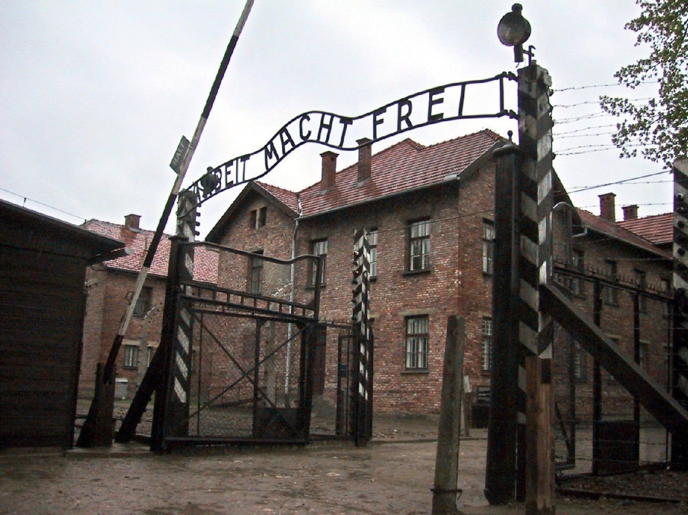 Außenansicht des Eingangsbereichs zum ehemaligen nationalsozialistischen Konzentrationslager Auschwitz-Birkenau mit der Inschrift "Arbeit macht frei" über dem Tor.