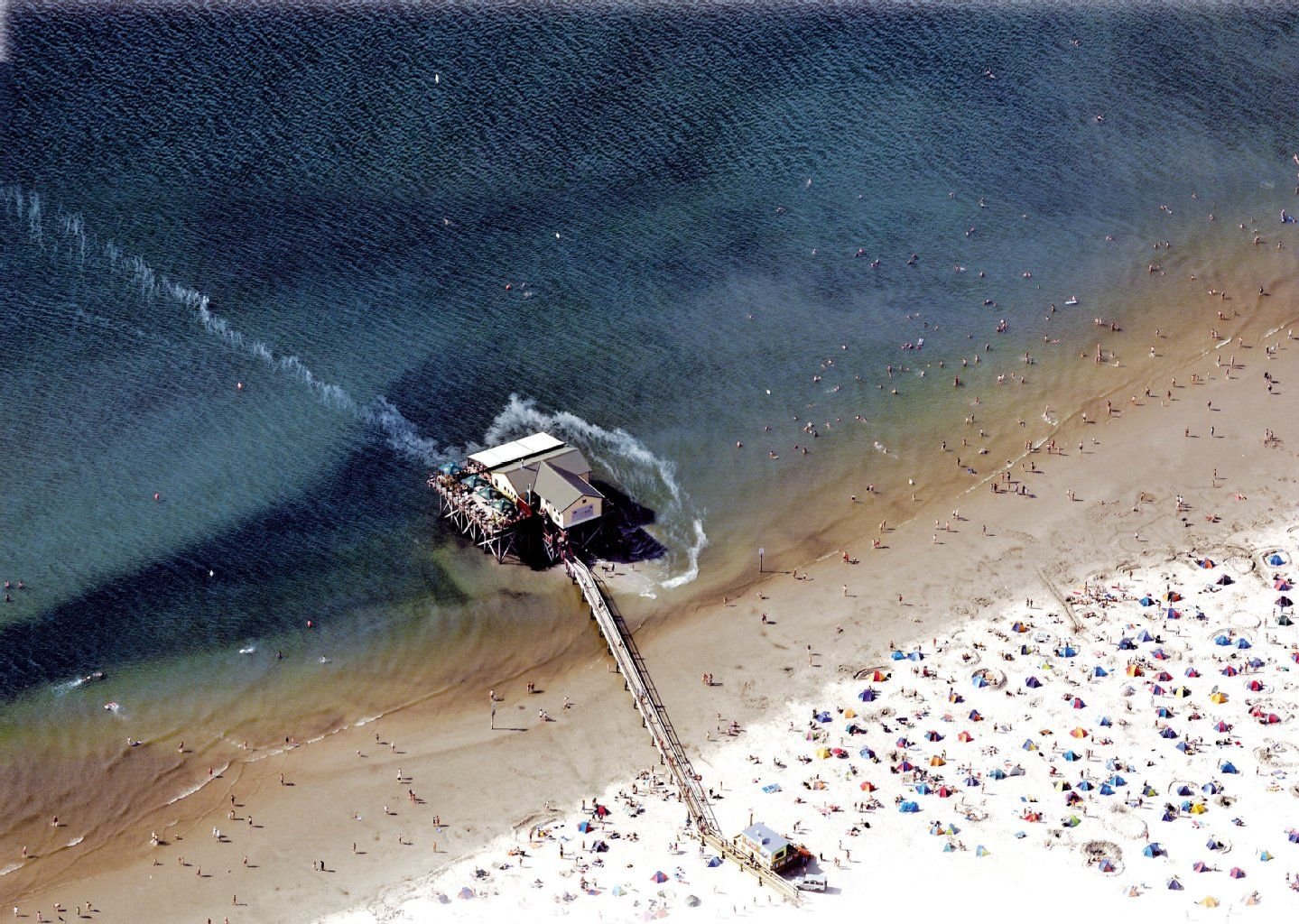 Ein Steg führt vom Strand in Sankt-Peter-Ording zum Stelzenhaus.