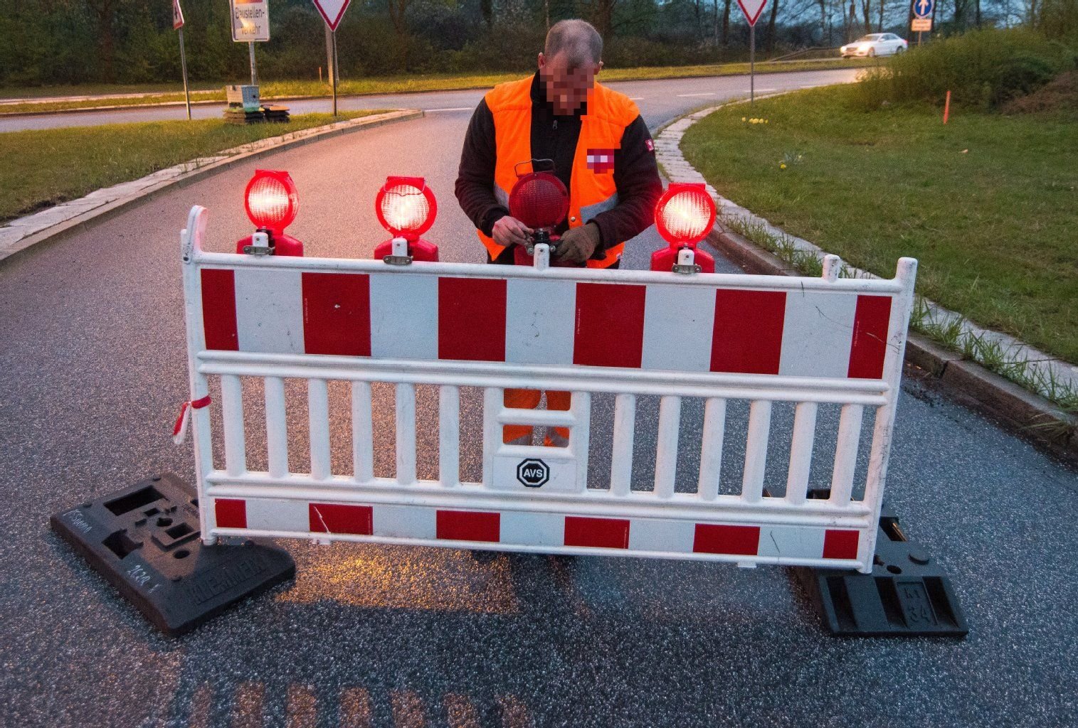 Ein Mitarbeiter der Straßensicherung markiert sperrt eine Straße.