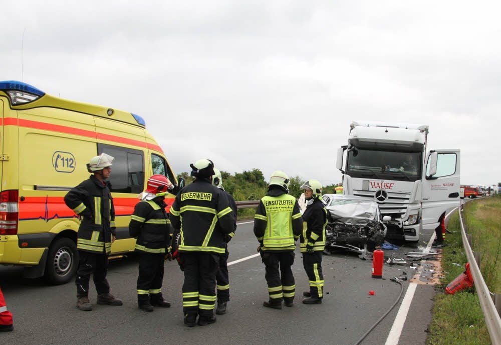 Feuerwehrleute vor dem völlig zertrümmerten Pkw.