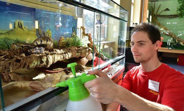 Vereinsmitglied Sebastian Damerau zeigt, wie die Gehege der Tiere gepflegt werden.