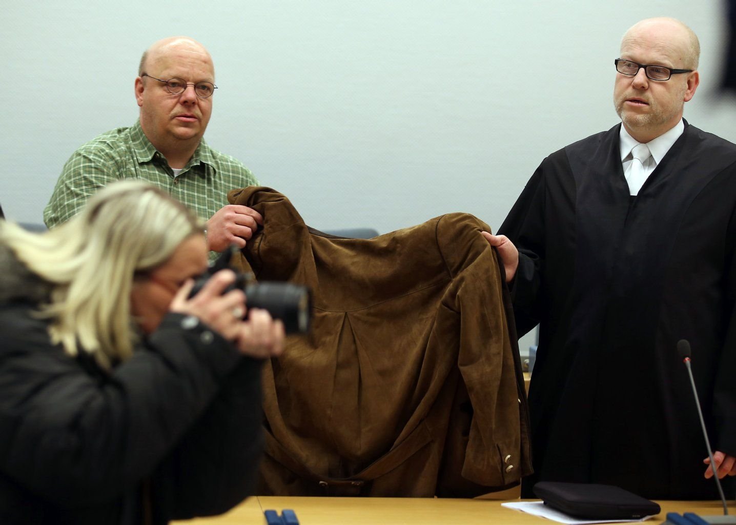 Die 32 Jahre alte Angeklagte wird im Landgericht von ihrem Anwalt Daniel Nierenz (r) und einem Anwaltsgehilfen (hinten links) mit einer Jacke verdeckt.