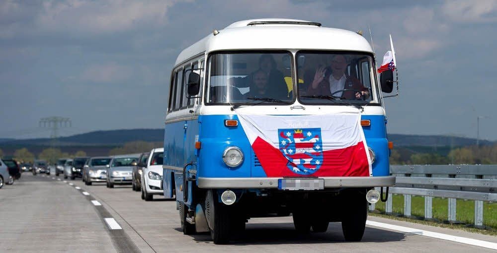 Ein Bus mit thüringischer Landesfahne fährt auf der gerade freigegebenen A71 zwischen Sangerhausen und Heldrungen.