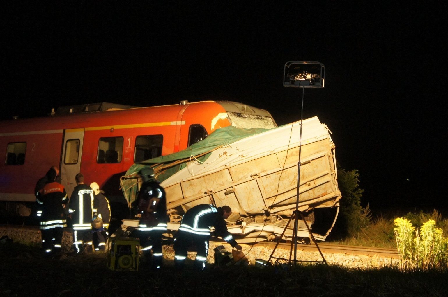 Beim Zusammenstoß eines Zuges mit einem Traktor sind in Könnern im Salzlandkreis (Sachsen-Anhalt) in der Nacht zum 11.08.2014 acht Menschen verletzt worden, Einsatzkräfte sichern die Unfallstelle.