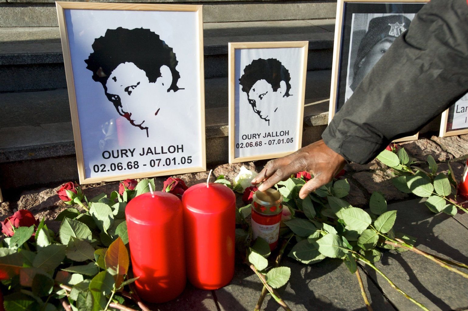 Rosen liegen vor dem Bild von Oury Jalloh am Hauptbahnhof in Dessau-Roßlau.