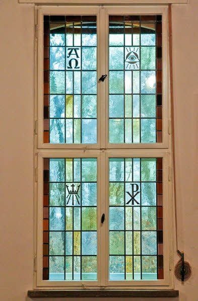Den Gemeinderaum zieren mehrere Buntglasfenster mit Motiven.