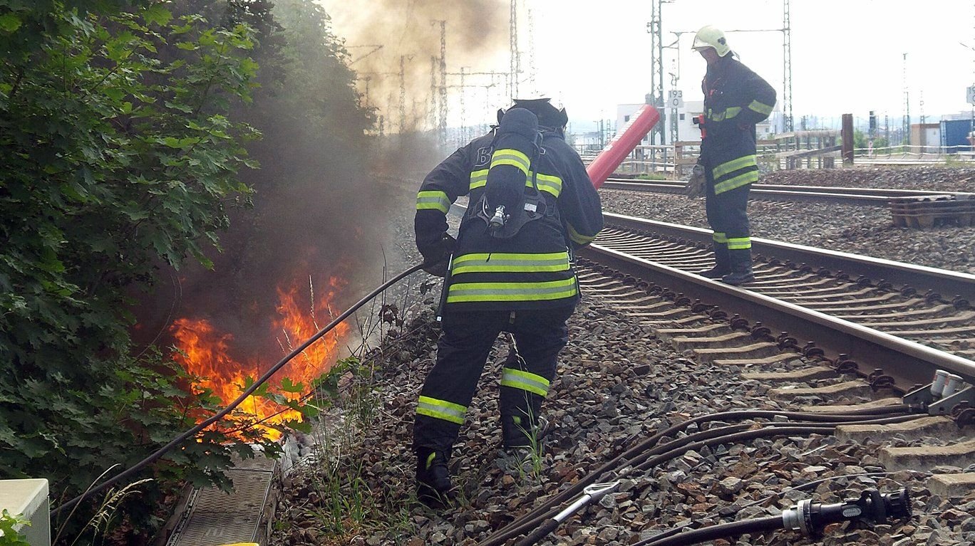 Feuerwehrleute löschen einen Kabelbrand an der Bahnstrecke zwischen Erfurt und Weimar.