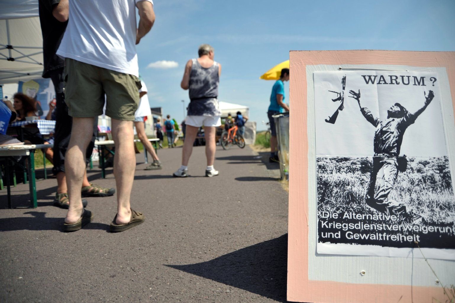 Teilnehmer gehen am Aktionscamp von Friedensaktivisten, unter dem Motto "War starts here", in Letzlingen an einem Plakat vorbei.