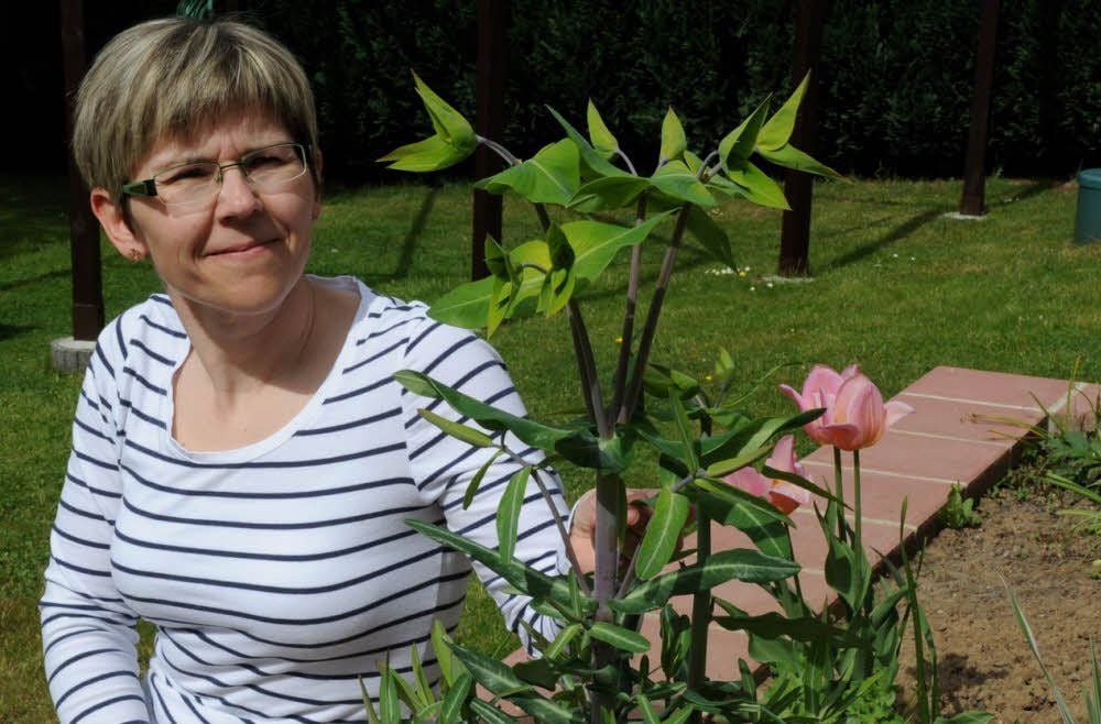 Kathleen Reuter sitzt im Garten in Siebigerode neben der unbekannten Pflanze.