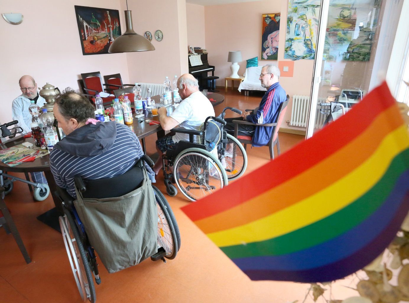 Eine Regenbogen-Fahne schmückt den Gemeinschaftsraum der Wohngemeinschaft für homosexuelle Senioren in Berlin, die sich um den Esstisch zum Mittagessen versammelt haben.