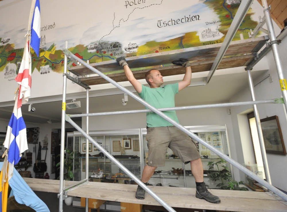Dennis Lärm von der Firma Kaphus aus Kühren entfernt das Gerüst und gibt den Blick auf das Bild frei.