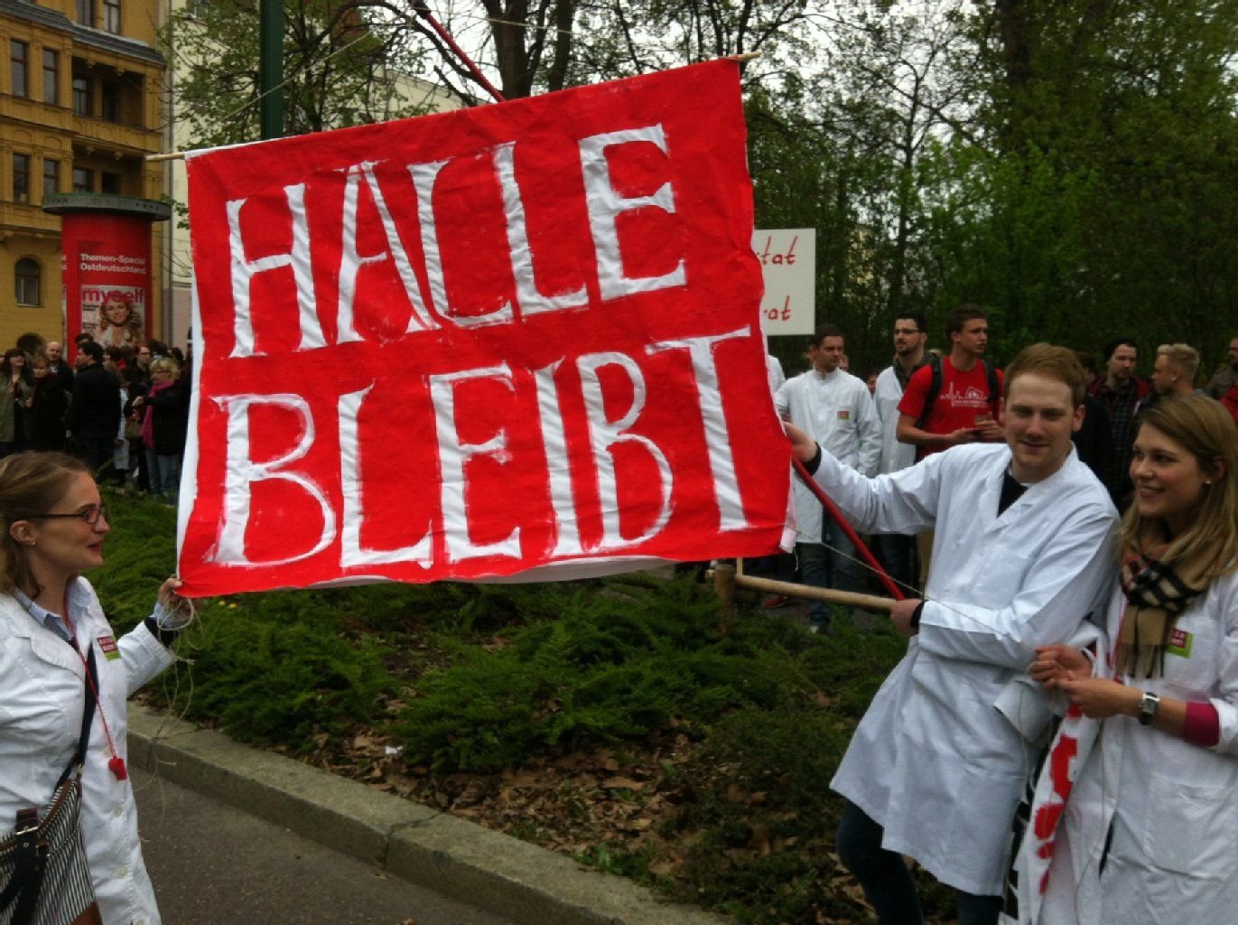 Zahlreiche Demonstranten tragen Arztkittel, Plakate und auch Rasseln.