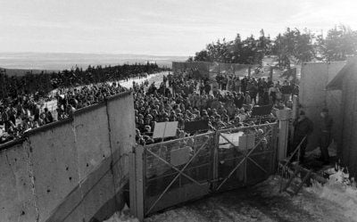 Menschen stehen am 03.12.1989 nach einer von der DDR-Bürgerbewegung organisierten «Wanderung» zum Brocken vor dem verschlossenen Tor zu den militärischen Einrichtungen auf dem Brocken und wollen die Öffnung erzwingen. (FOTO: DPA)