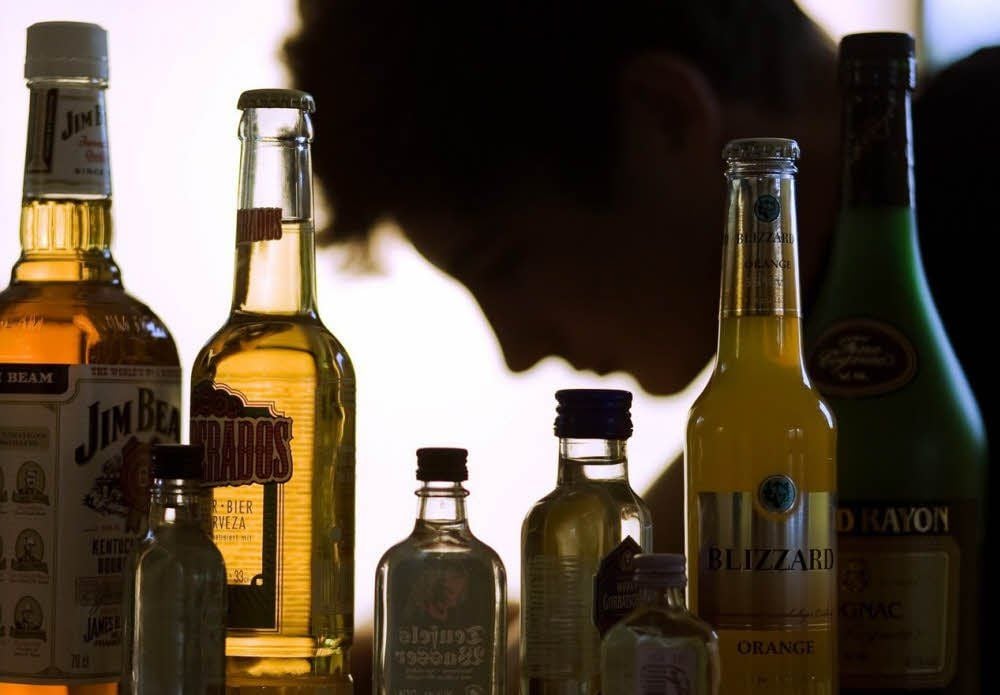 Flaschen mit alkoholhaltigen Getränken stehen vor einem Jugendlichen.