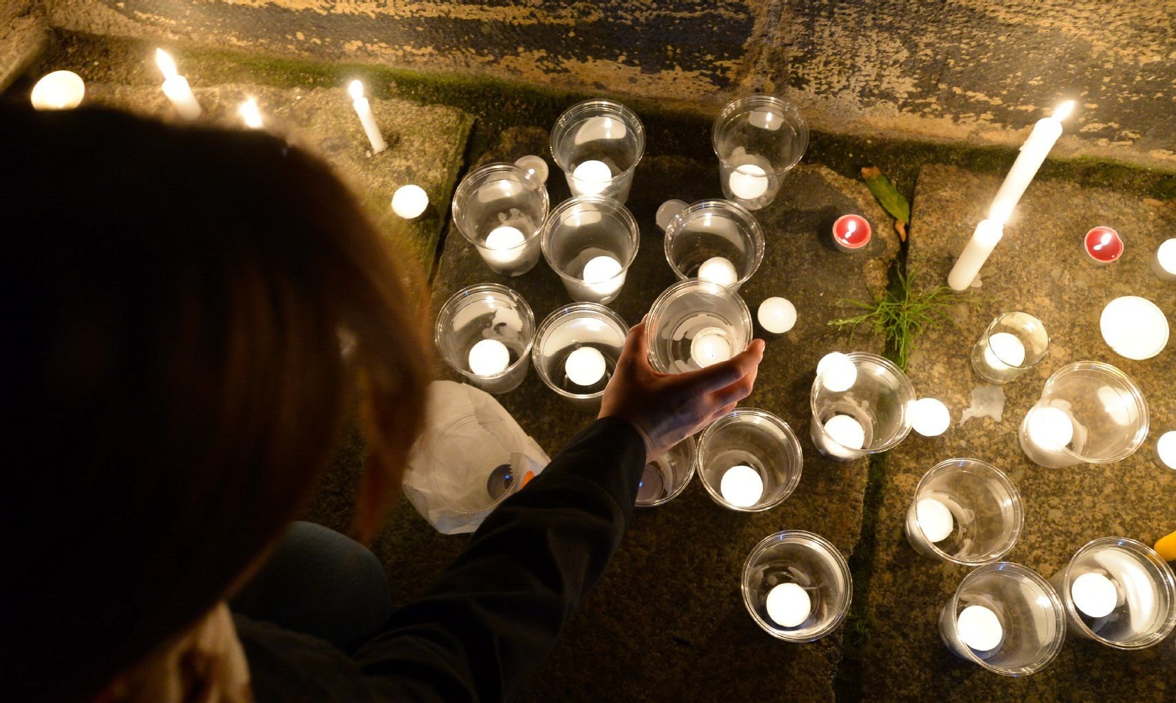 Eine Frau stellt eine Kerze an die Nikolaikirche zum Lichtfest.