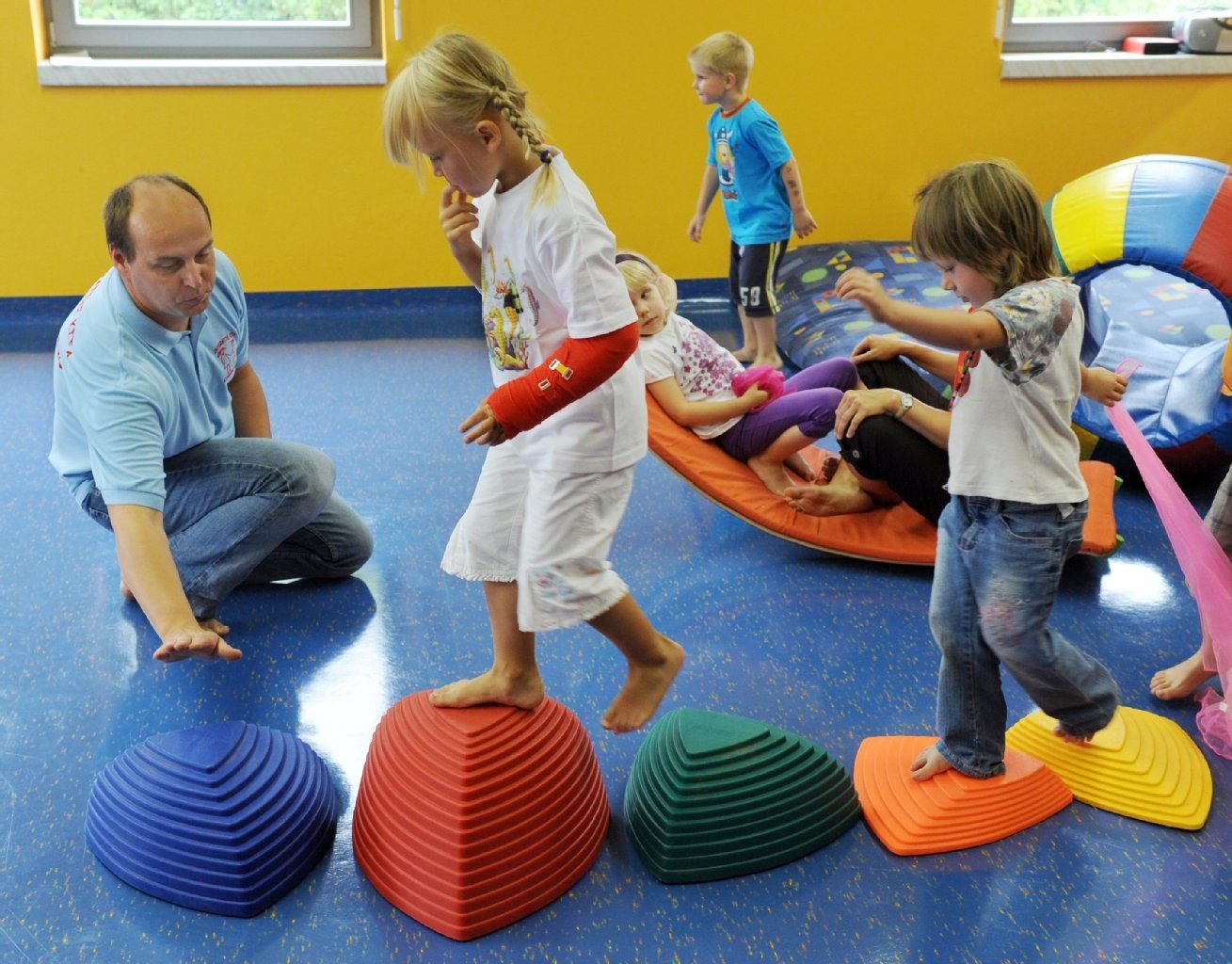 Ein Erzieher übt in einer Kindertagesstätte mit den Kindern balancieren.