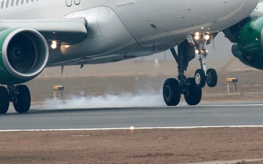Ein Reifen qualmt beim Aufsetzen eines landenden Flugzeugs.