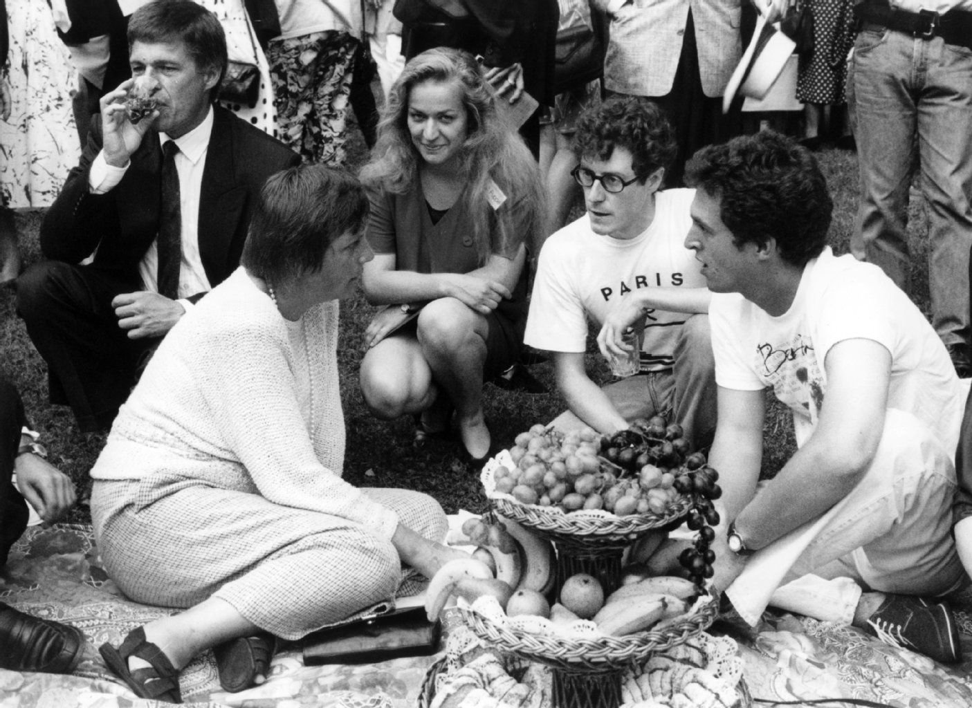 Die damalige Bundesministerin für Familie und Jugend, Angela Merkel (l, CDU) unterhält sich am 22.08.1992 auf dem Boden sitzend mit Studenten des 42. Internationalen Jugendfestspieltreffens beim traditionellen Picknick im Park des Festspielhauses in Bayreuth