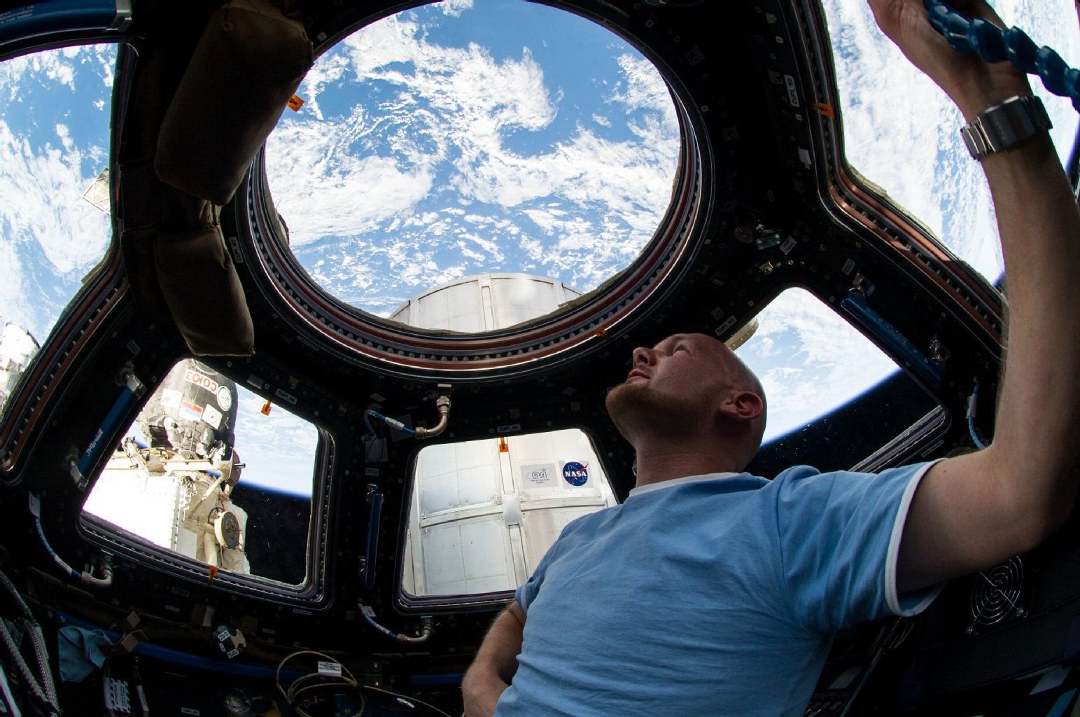 Alexander Gerst blickt aus den Fenstern einer Kuppel der ISS.