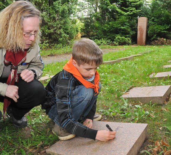 Angelo zeichnete mit Geduld die Buchstaben auf dem Grabstein nach. Betreuerin Angela Degenhardt erklärte ihm, um welche Menschen es sich handelte.