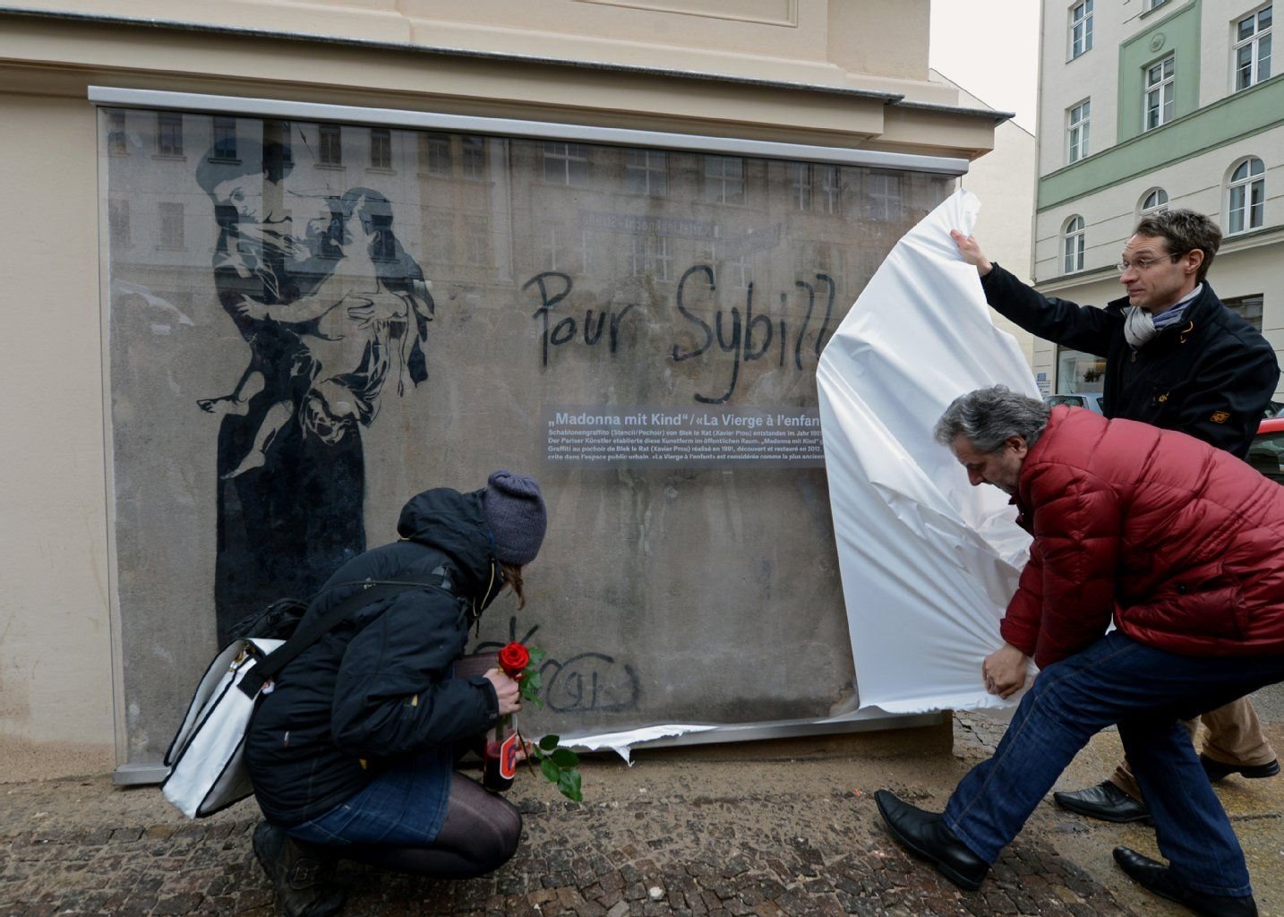 Das restaurierte Graffito "Madonna mit Kind" enthüllen Ansgar Scholz vom Kulturamt Leipzig und Immobilieninvestor Horst Langner (v.r.) am 12.04.2013 in der Südvorstadt von Leipzig. Geschützt hinter einer Glasscheibe wird das wiederentdeckte Schablonengraffito des Streetart-Künstlers Blek Le Rat von 1991 dauerhaft im öffentlichen Raum erlebbar bleiben.