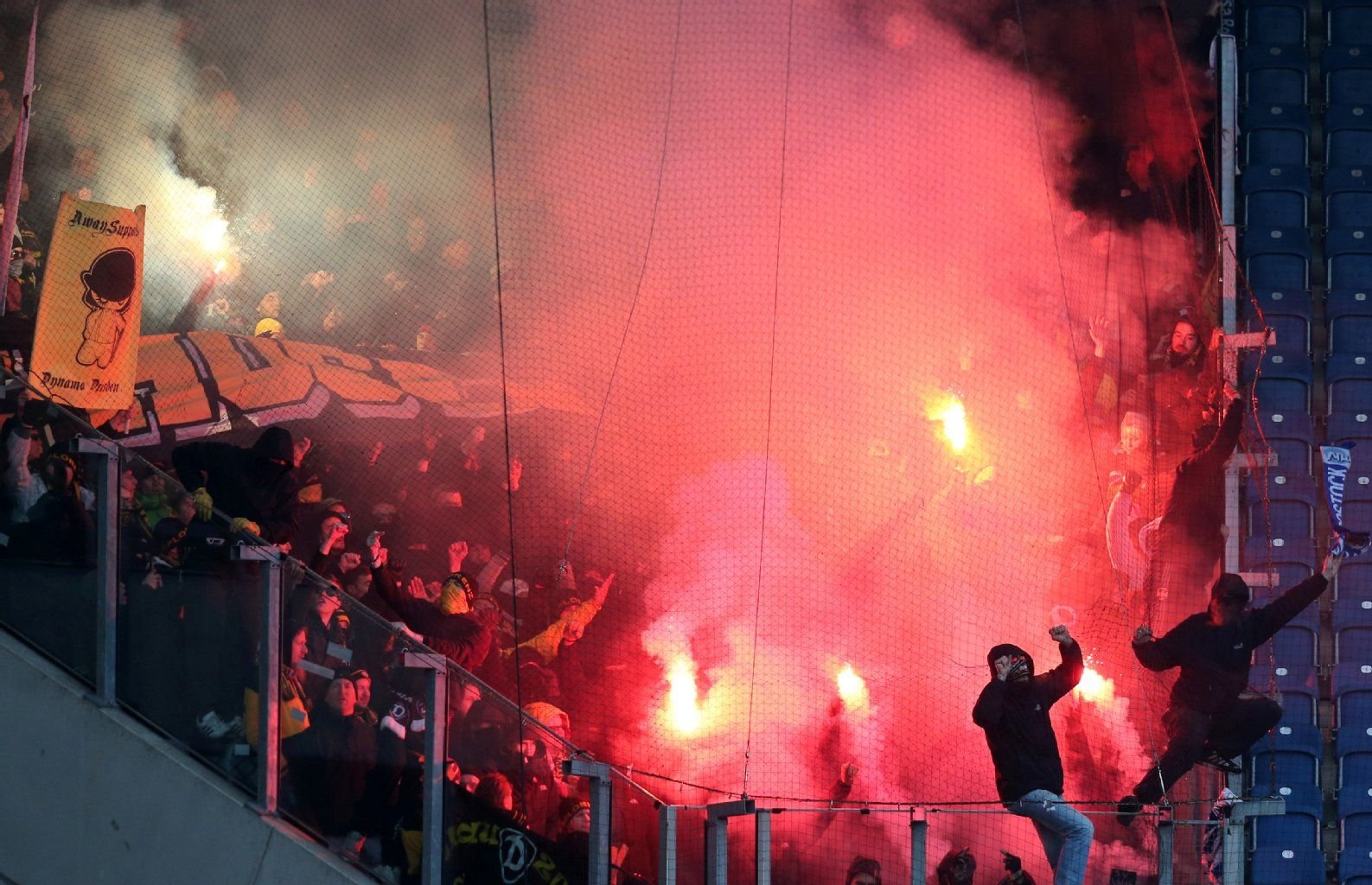 Dynamo-Anhänger zünden in Rostock bengalische Feuer und schießen Leuchtspuren auf andere Tribünen.
