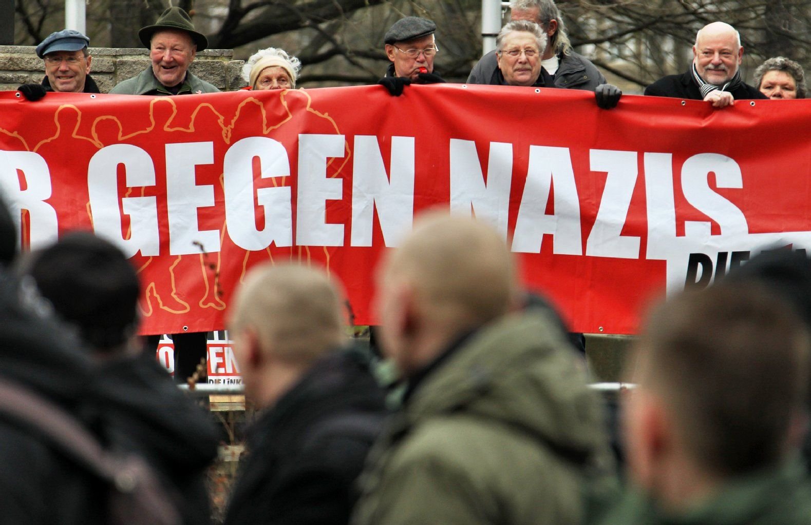 Mit einem Transparent protestieren Bürger gegen einen Aufzug von Rechtsextremen (vorne im Bild) in Dessau-Roßlau.