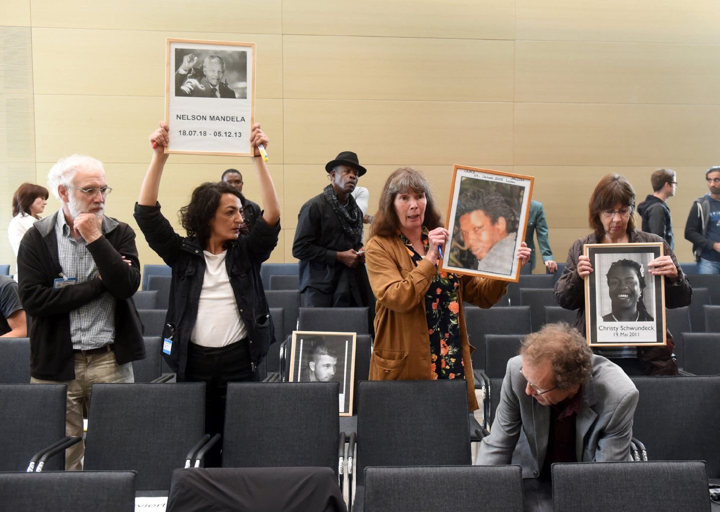 In einem Sitzungssaal des Bundesgerichtshofs (BGH) in Karlsruhe halten nach der Urteilsverkündung zum Feuertod in Dessau 2005 von Ouri Jalloh Besucher Bilder in die Höhe.