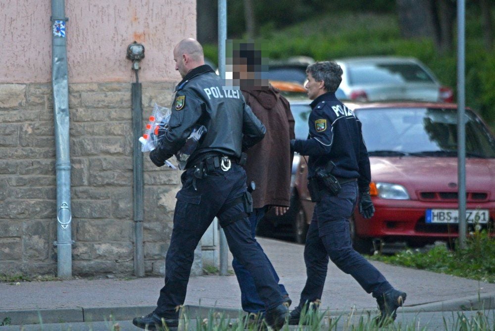 Ein Verdächtiger wird von Polizeibeamten abgeführt.