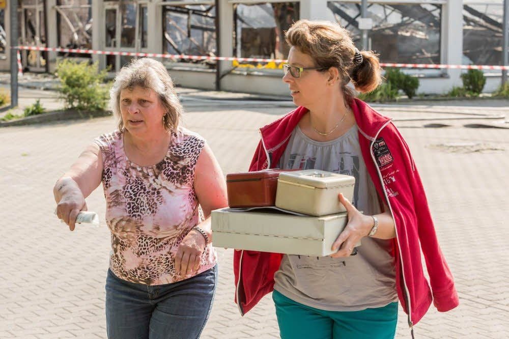 Regina Ziegler (links) am Brandort: Die 62-jährige Miteigentümerin des Bad Bibraer Einkaufszentrums Bibertalcenter versucht gemeinsam mit ihrer Tochter, einige Dinge aus dem stark zerstörten Gebäude zu retten.
