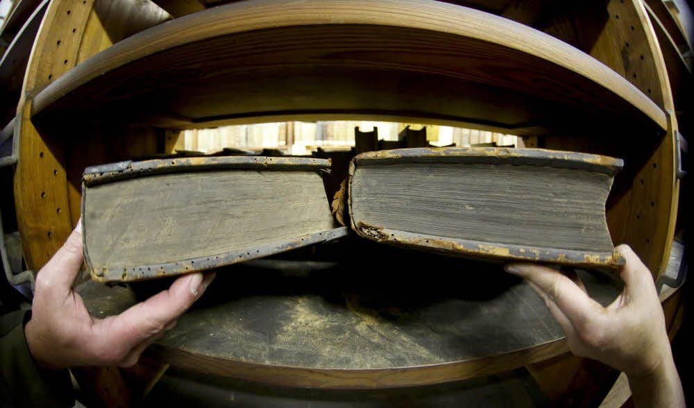 In der Marienbibliothek hat der Holzwurm Spuren hinterlassen: Holzmehl im Regal und die Ausfluglöcher des Nagekäfers in den Deckeln.