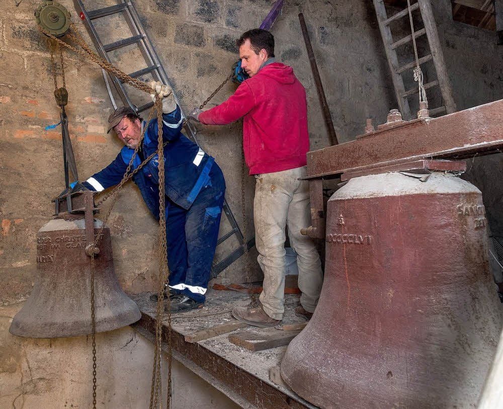 Wilfried Förster (l.) und Patrick Fritsche lassen die erste der drei Glocken mittels Flaschenzug aus dem Kirchturm herab.