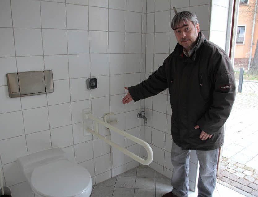 Frank Weidauer vom Senioren- und Behindertenbeirat Hohenmölsens zeigt, wie weit entfernt die Klorolle vom WC-Becken angebracht ist.