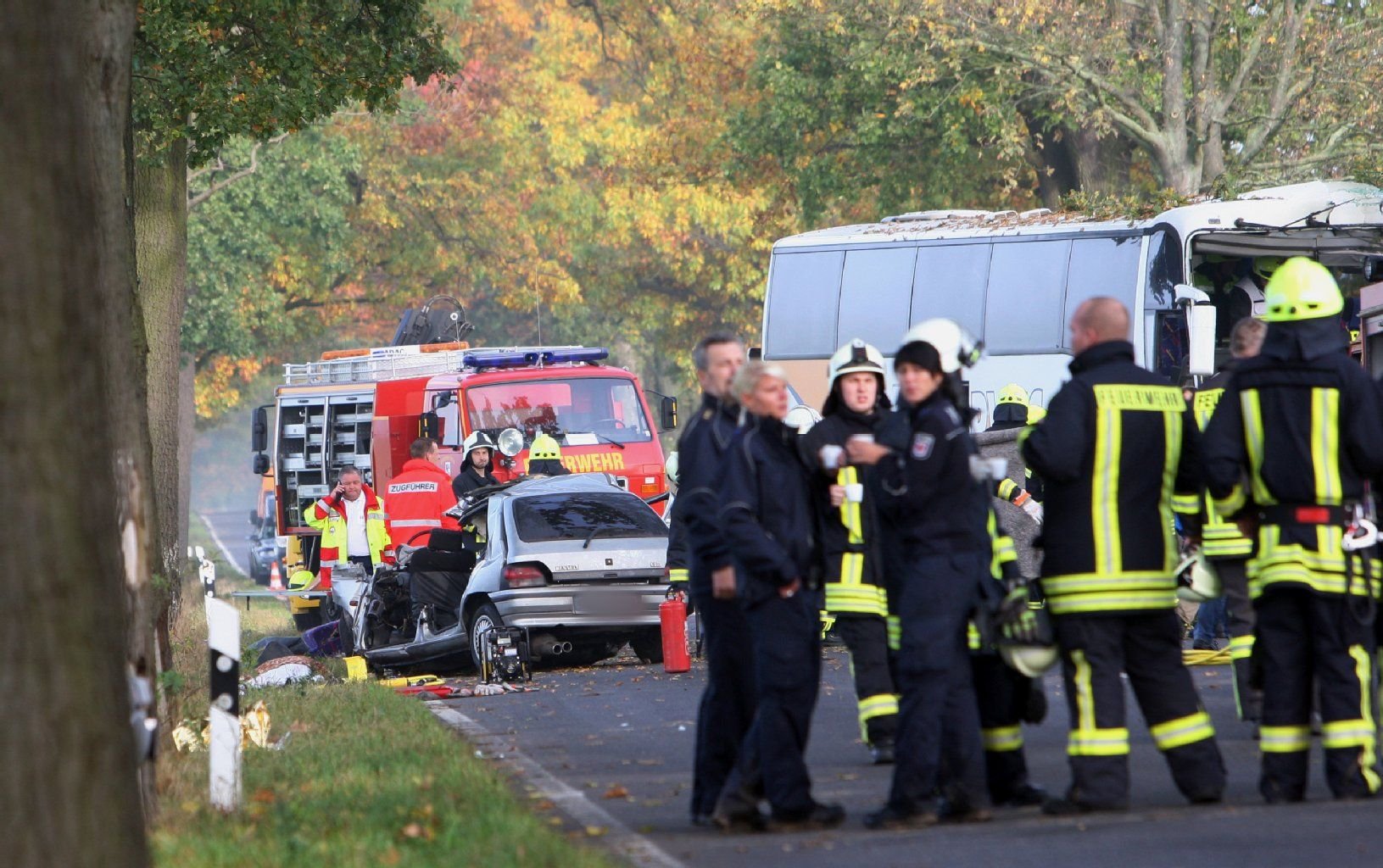 Rettungskräfte stehen neben einem zerstörten Reisebus und dem Wrack eines PKW am 18.10.2014 auf der B5 zwischen Pessin und Friesack (Brandenburg). Bei einem Frontalzusammenstoß von einem Auto und einem Reisebus sind zwei Menschen gestorben.