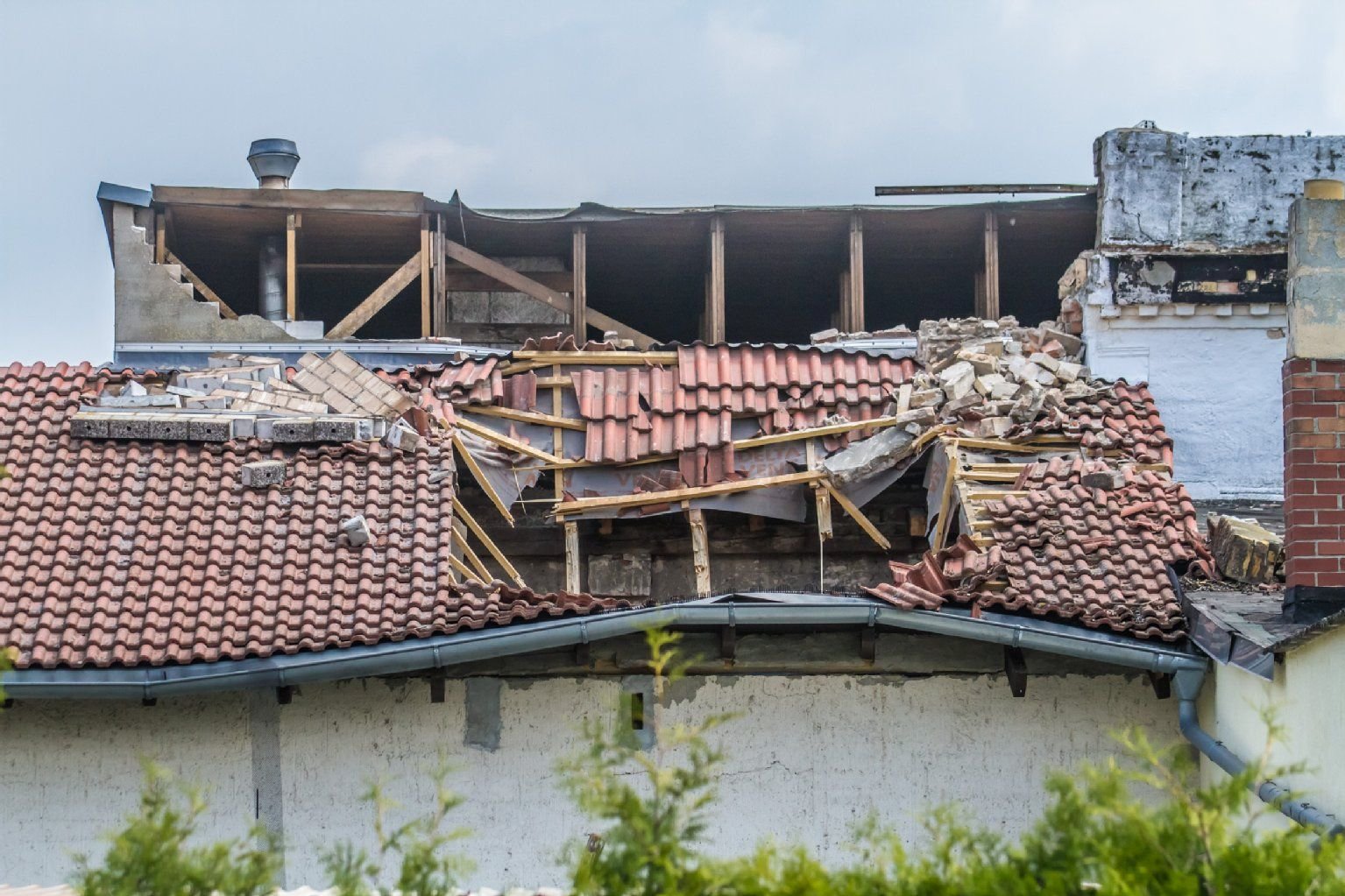 Die Mauerkrone eines angrenzenden Hauses hat das Dach des Einfamilienhauses durchbrochen.