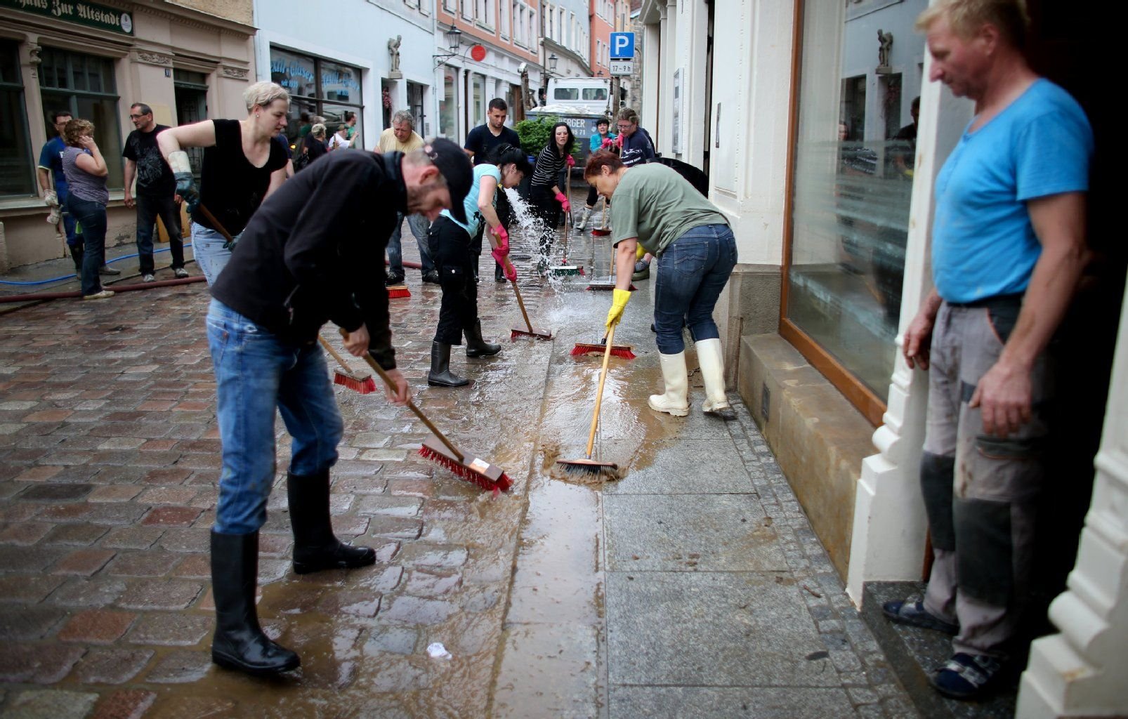 Helfer fegen in der vom Elbehochwasser betroffenen Altstadt von Meißen (Sachsen) Schlamm von der Straße.