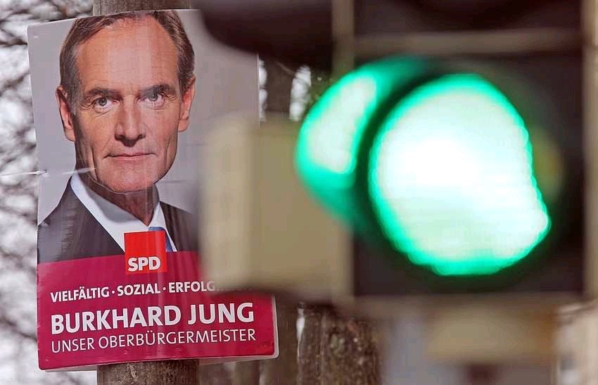Ein Wahlplakat von Amtsinhaber Burkhard Jung (SPD) hängt hinter einer grünen Ampel in Leipzig.