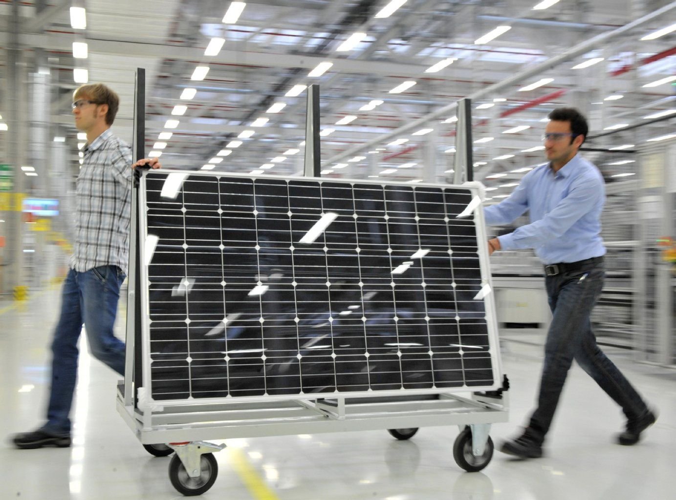 Mitarbeiter transportieren in einer Fertigungshalle der Bosch Solar Energy AG in Arnstadt ein Solarmodul.