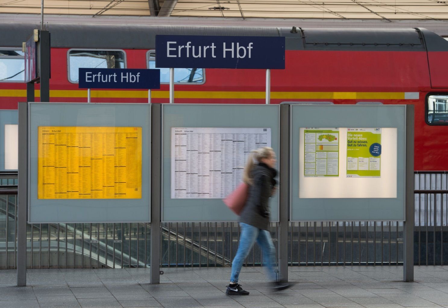 Eine Frau geht auf dem Hauptbahnhof in Erfurt (Thüringen) an einer Anzeigetafel vorbei.
