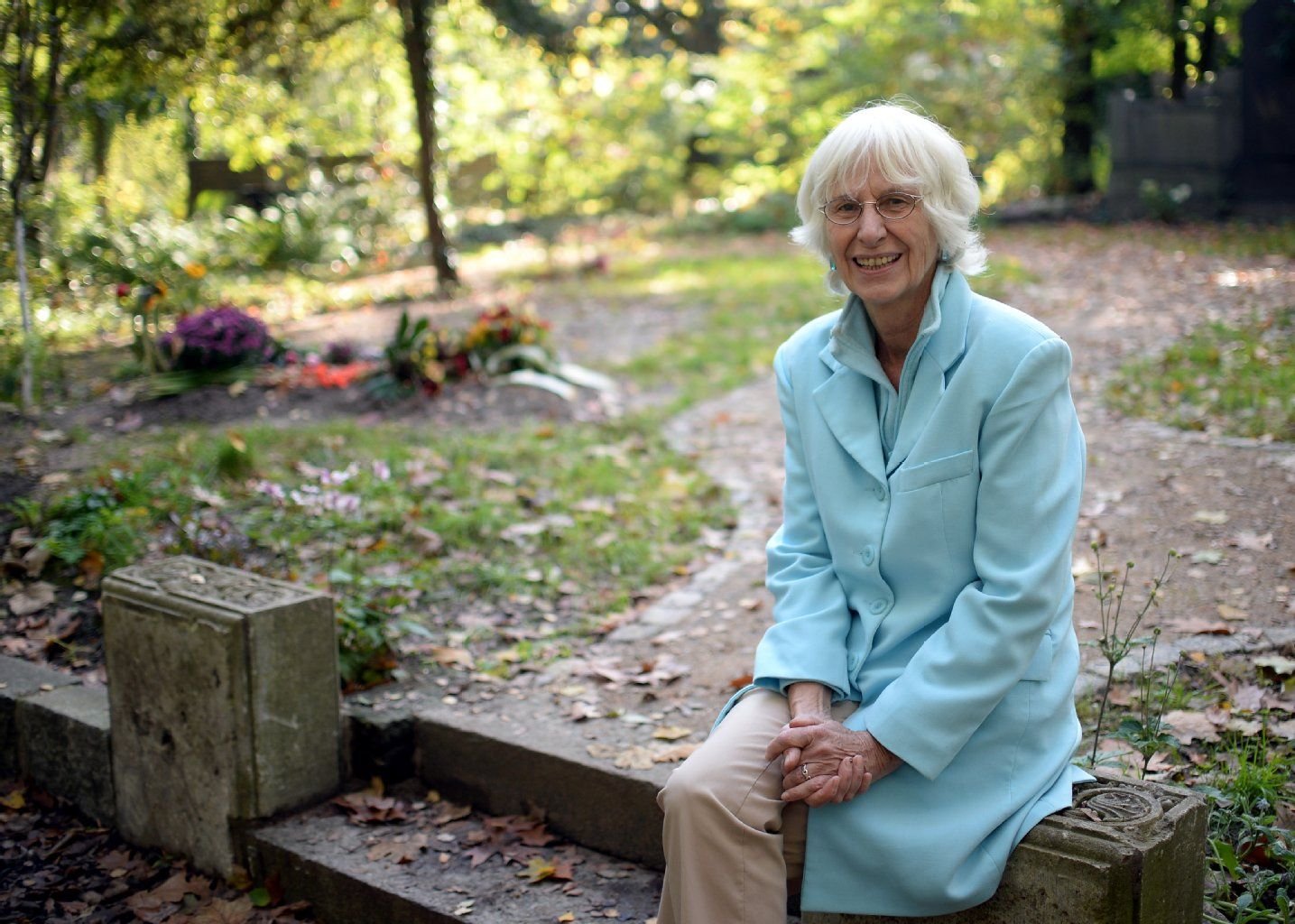 Astrid Osterland sitzt auf dem Georgen-Parochial-Friedhof I in Berlin an einem Grab.