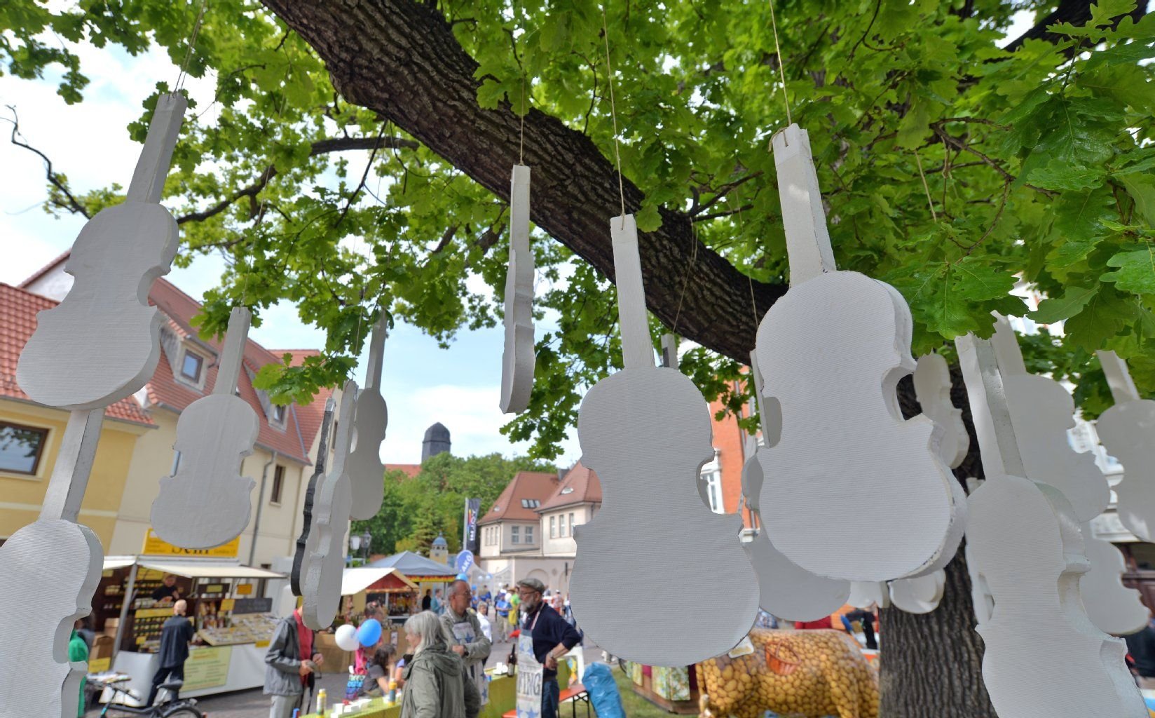 Stilisierte Violinen hängen zum 19. Sachsen-Anhalt-Tag in Köthen in einem Baum.