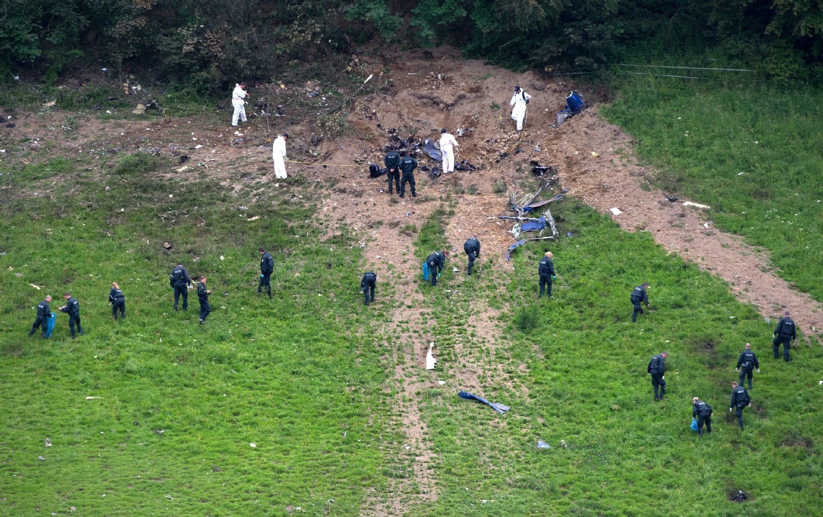 Ermittler der Bundesstelle für Flugunfalluntersuchung und Polizisten untersuchen auf einer Wiese bei Elpe die Absturzstelle eines Learjets.