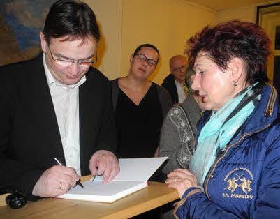Berührt von der Lesung lassen sich Besucher das Buch von Uwe Schwarz signieren. Melanie Engler von der Prettiner KZ-Gedenkstätte (2.v.l.) zeigt sich beeindruckt.