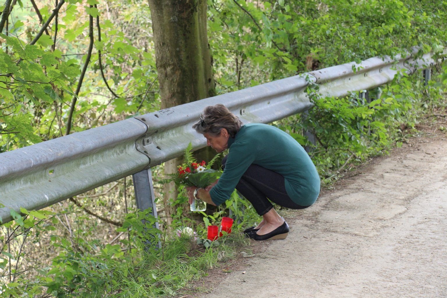 An eine Leitplanke direkt neben dem Absturzkrater in Olsberg legt Anwohnerin Brigitte Sulzmann am 27.06.2014 Blumen und Kerzen